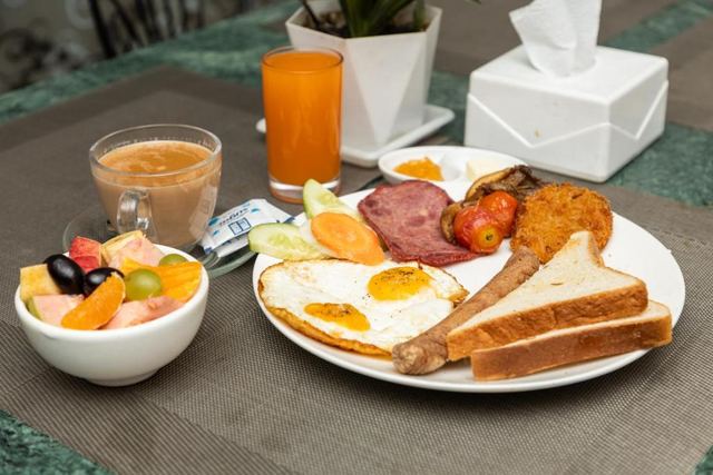 Breakfast with eggs, toast, sausage, fruit, juice and tea